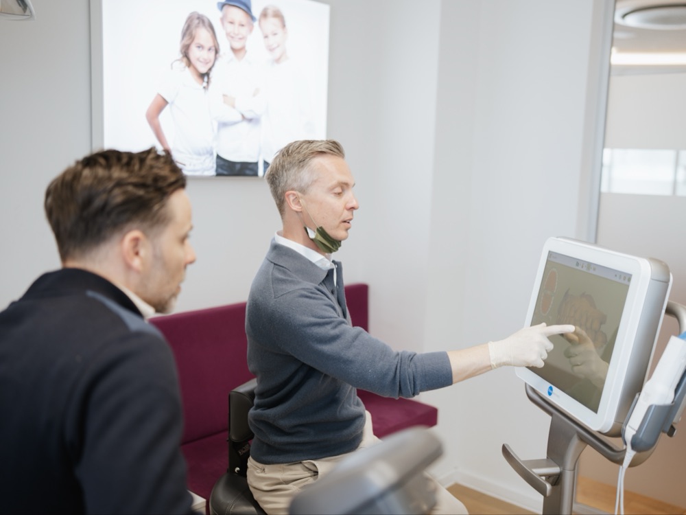 Ein Patient bekommt den 3D-Scan seiner Zähne am Scanner gezeigt